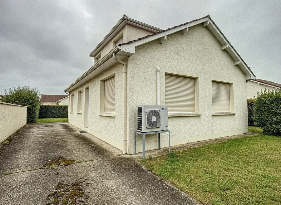 Groupe extérieur de pompe à chaleur contre un pavillon des Provinces à Laxou